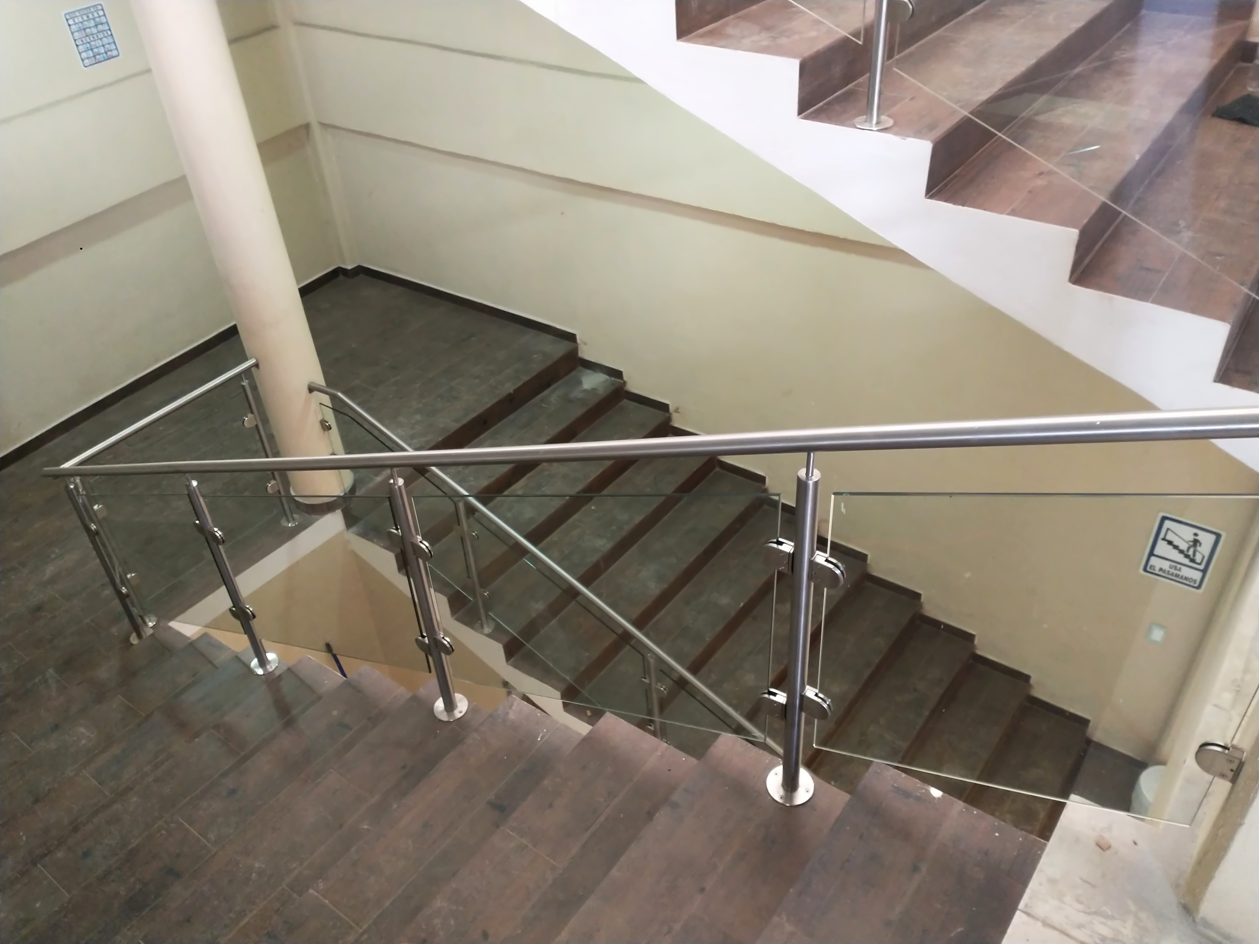 Barandal de cristal templado y pasamanos satinado en escalera interior de oficinas