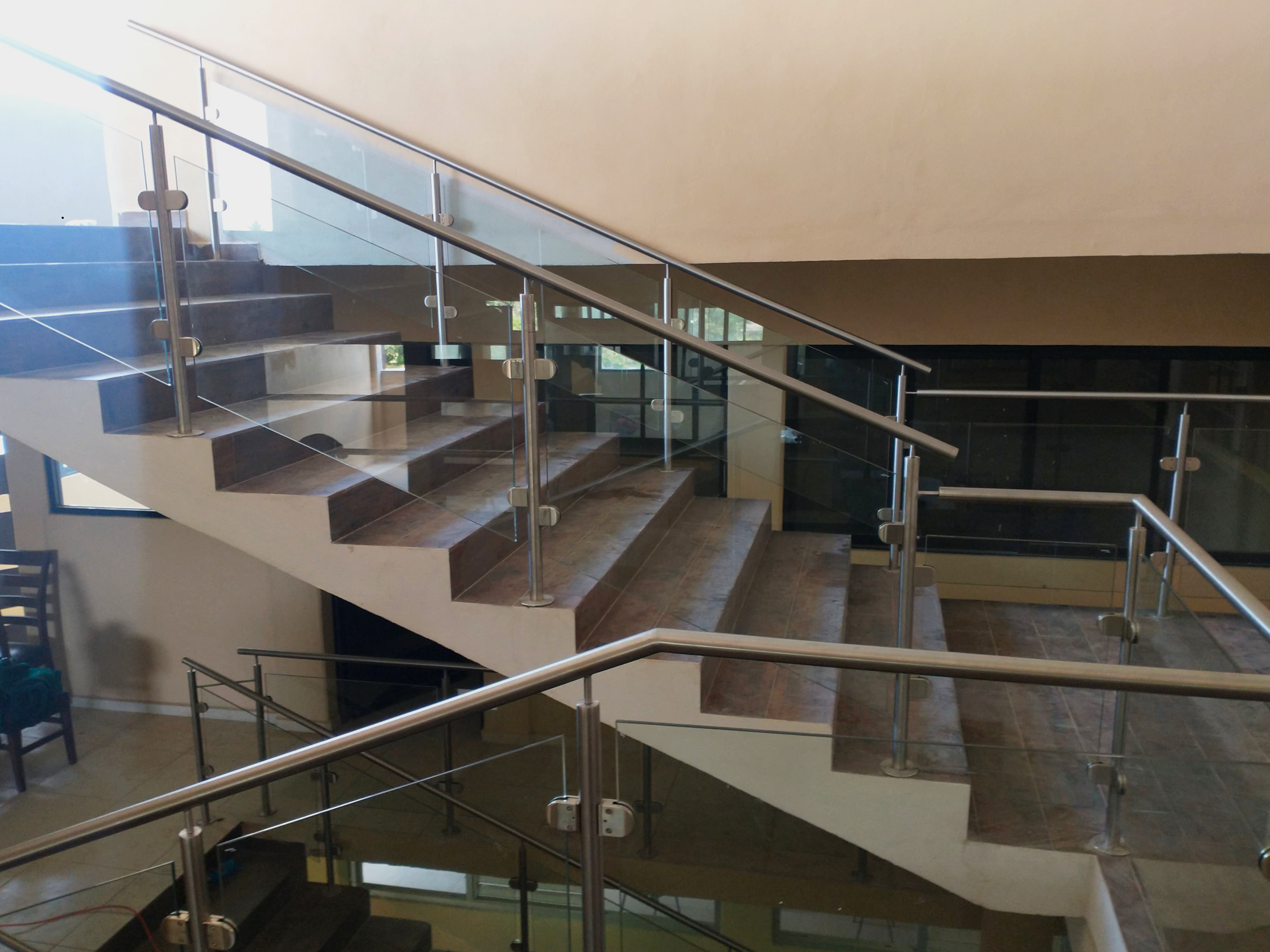 Barandal de vidrio y acero inoxidable acompañando escalera flotante