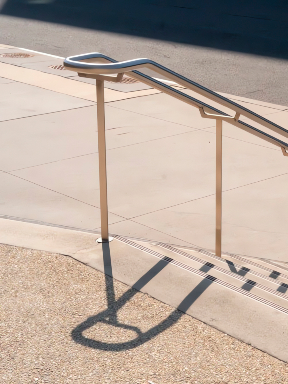 Pasamanos de acero inoxidable con curva ergonómica instalado en escaleras públicas de concreto